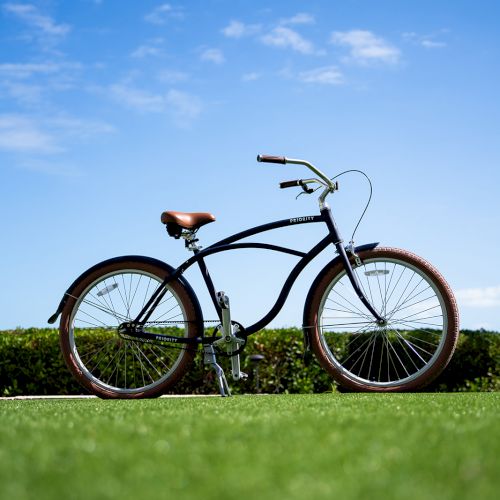 A bicycle stands on a grassy field under a clear blue sky with scattered clouds.